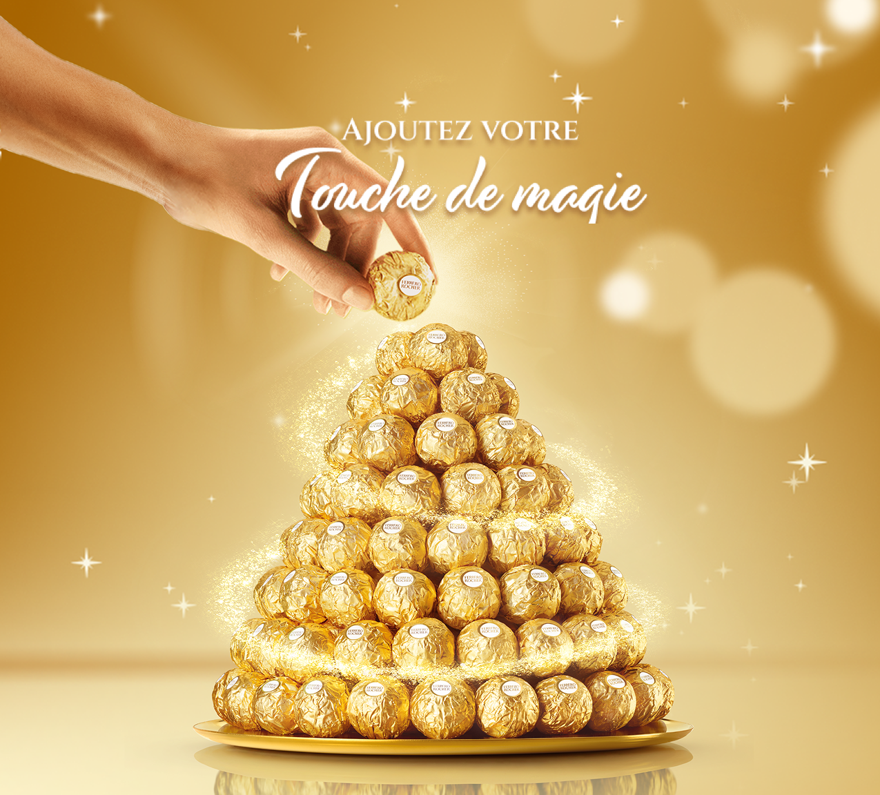 Une main déposant un Ferrero Rocher au sommet d’une pyramide de friandises Ferrero Rocher