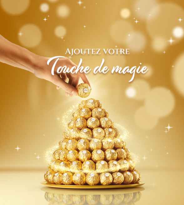 Une main déposant un Ferrero Rocher au sommet d’une pyramide de friandises Ferrero Rocher